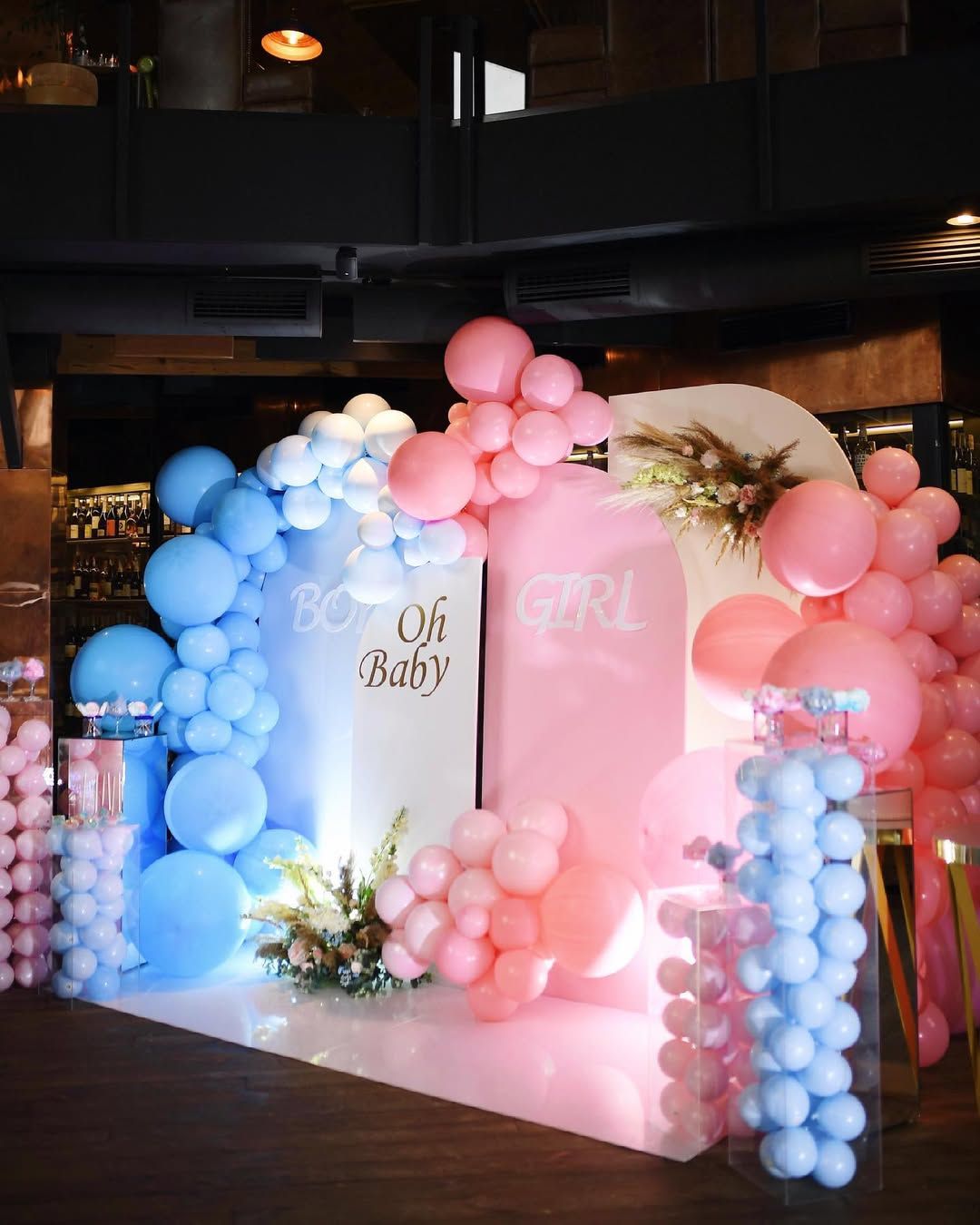 A stunning indoor photo zone featuring a pink and blue balloon arch for an elegant gender reveal and baby shower in Valencia.