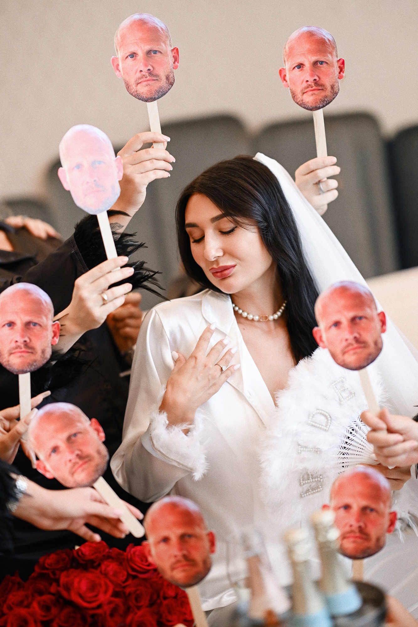 Playful moment during a Valencia hen weekend, as the bride sits surrounded by friends holding funny cardboard groom masks.