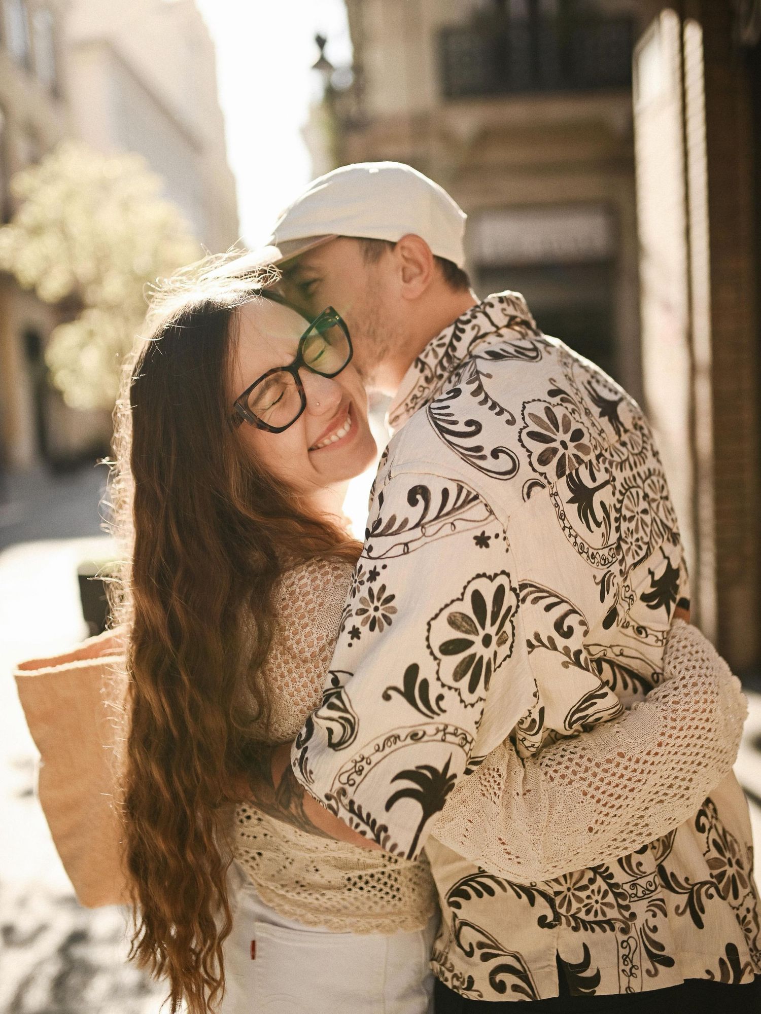 A loving man kissing his partner on the cheek during an intimate and emotional embrace on a city street in Valencia.