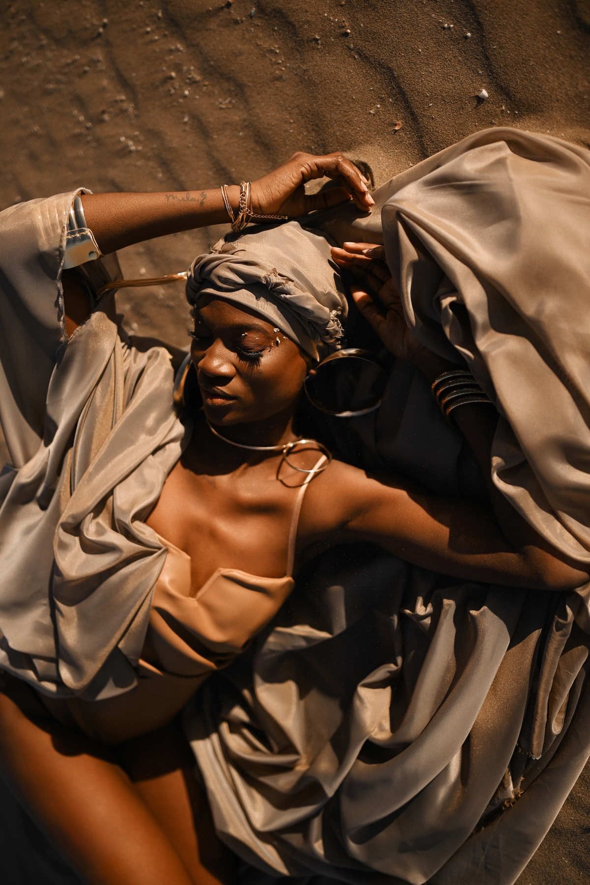 High-end editorial photography featuring a model in flowing silk posing on desert dunes for a fashion campaign.