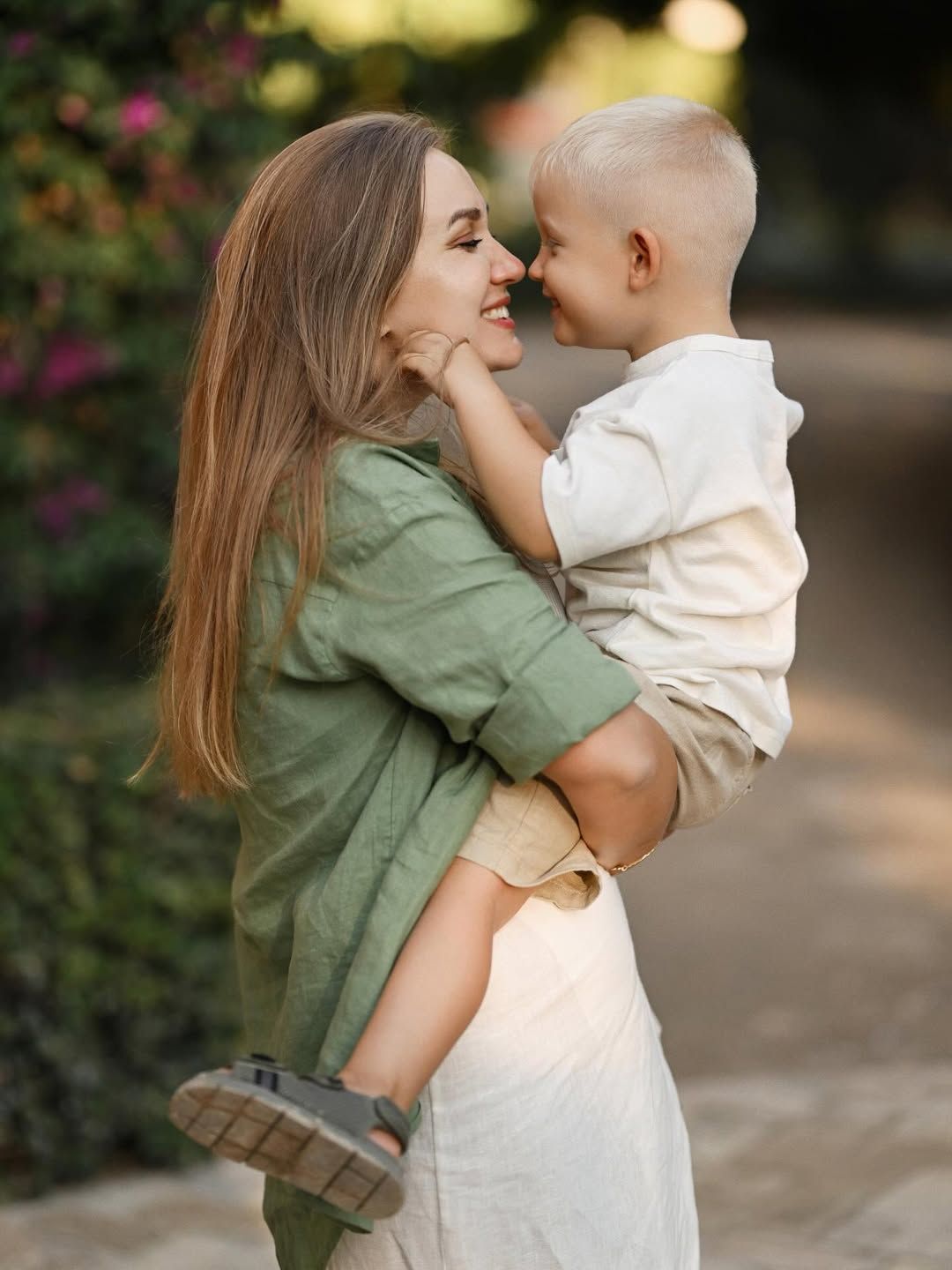 A mother smiling and hugging her young son during an outdoor family session in Turia Park, Valencia.