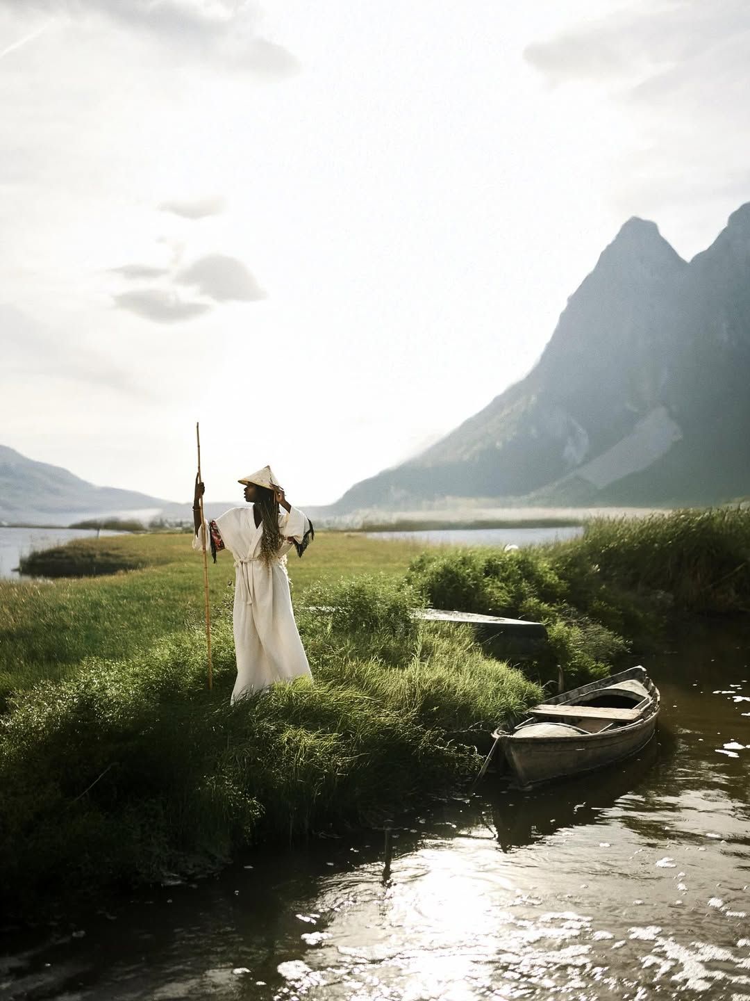 Scenic wide shot by a Valencia photographer showing a woman in an ethnic outfit with a rustic boat in the Albufera lagoon