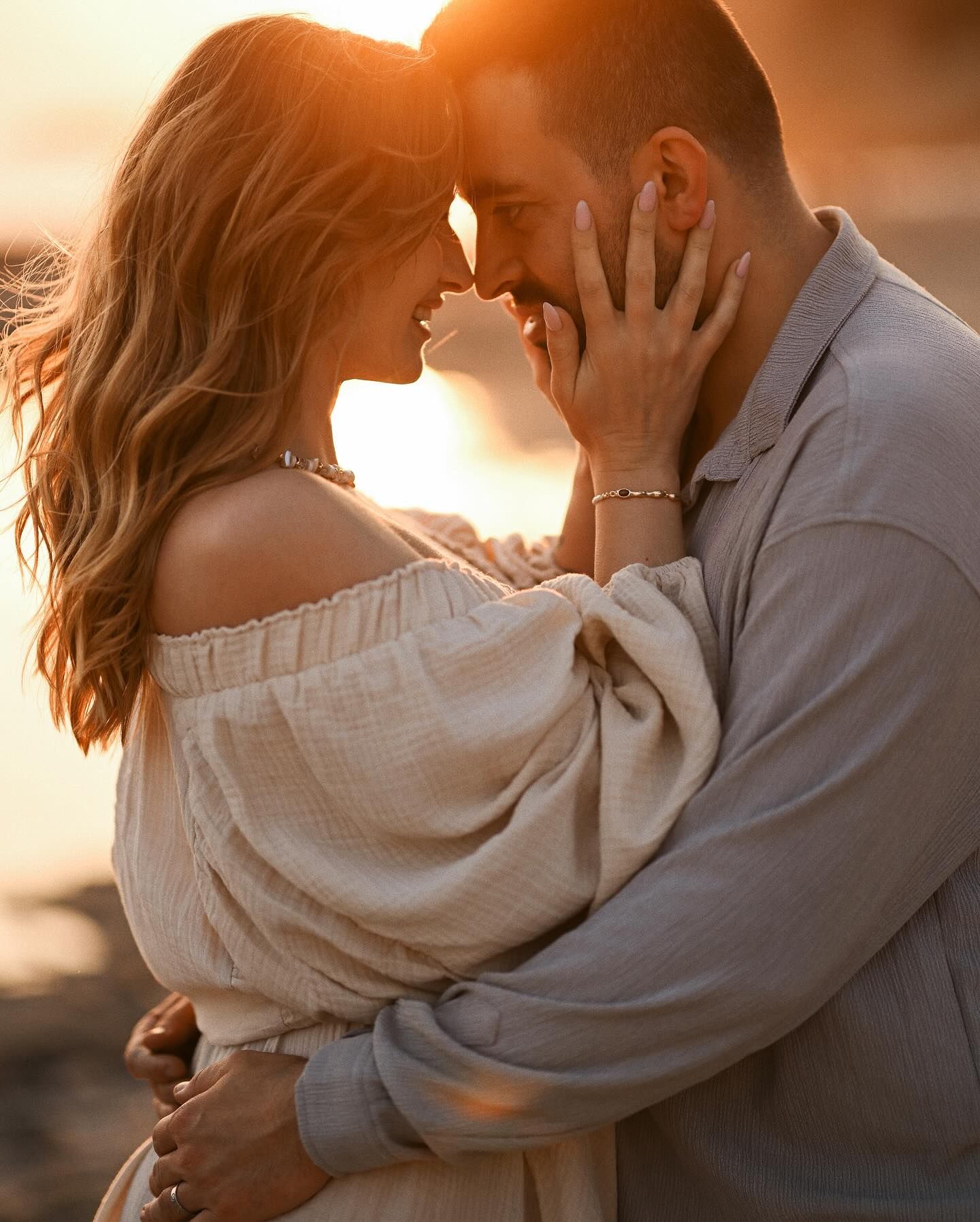 Close-up romantic portrait of a man and woman touching foreheads during a warm sunset photoshoot on the Costa Blanca coast.