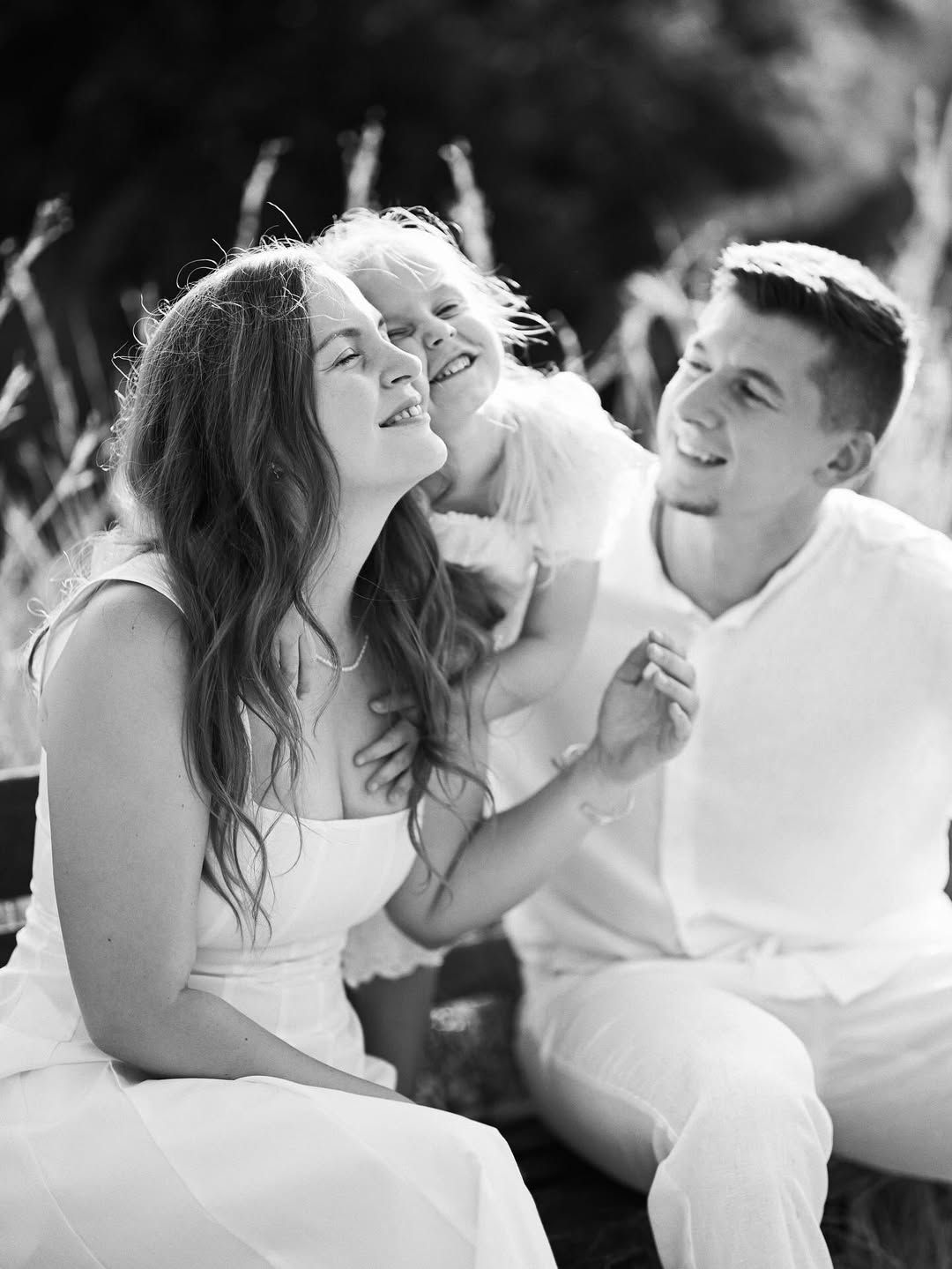A black and white close-up of a happy family sharing a joyful moment and laughter in an outdoor park setting.