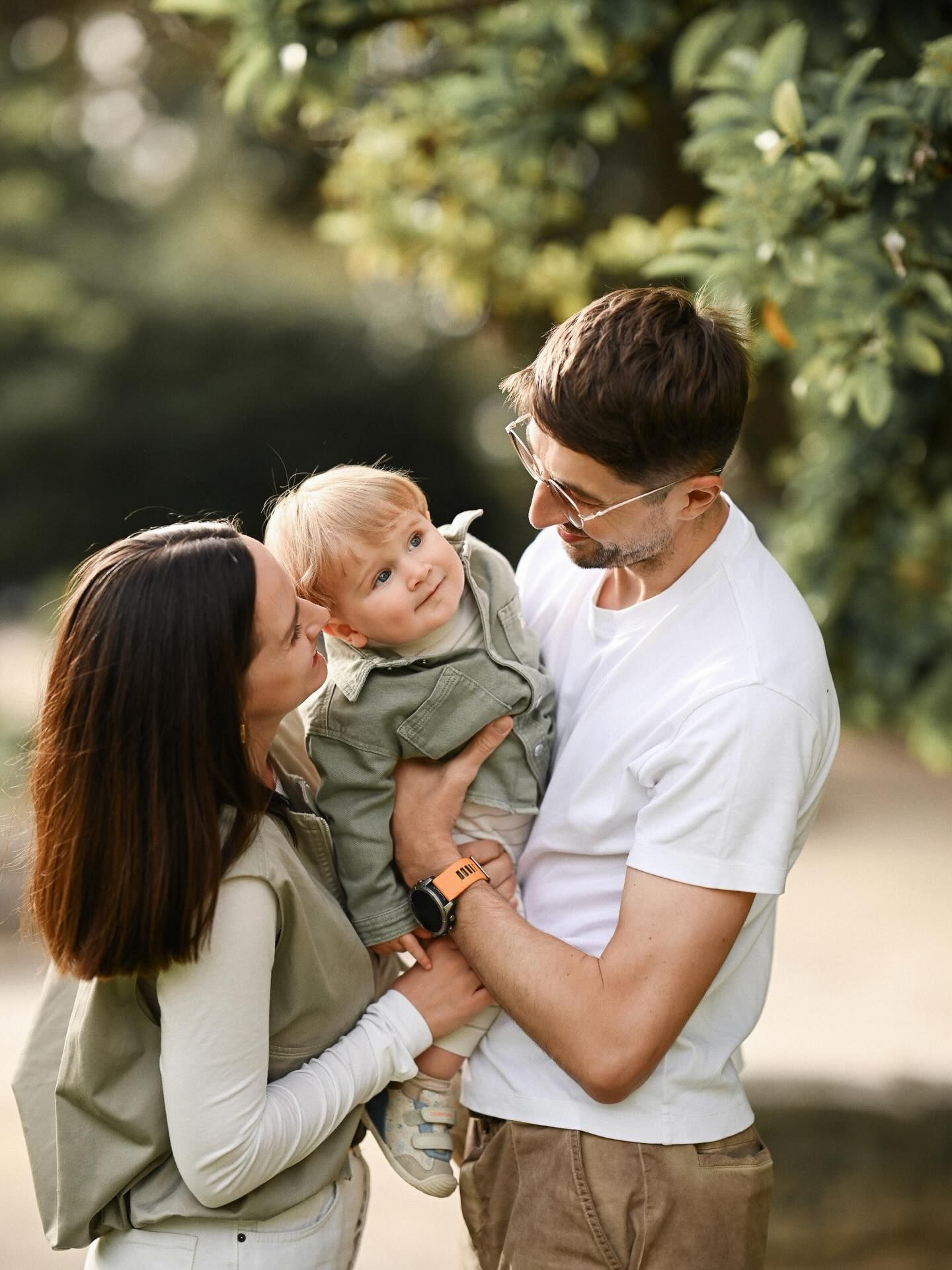 Medium shot of a mother and father holding their 6-9 month old baby boy outdoors during a lifestyle family session in Valencia.