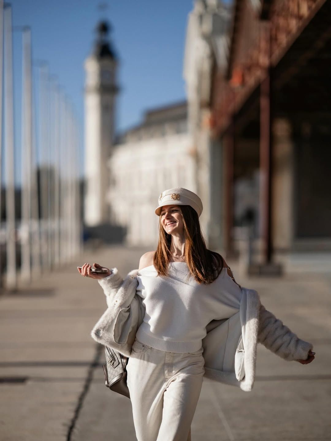 Woman walking and smiling during a lifestyle portrait photoshoot at Valencia Marina with historic clock tower in the background