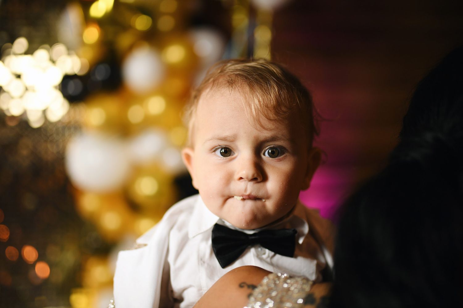 Adorable close-up of a baby boy with cake crumbs on his lips, looking directly into the camera during his party.