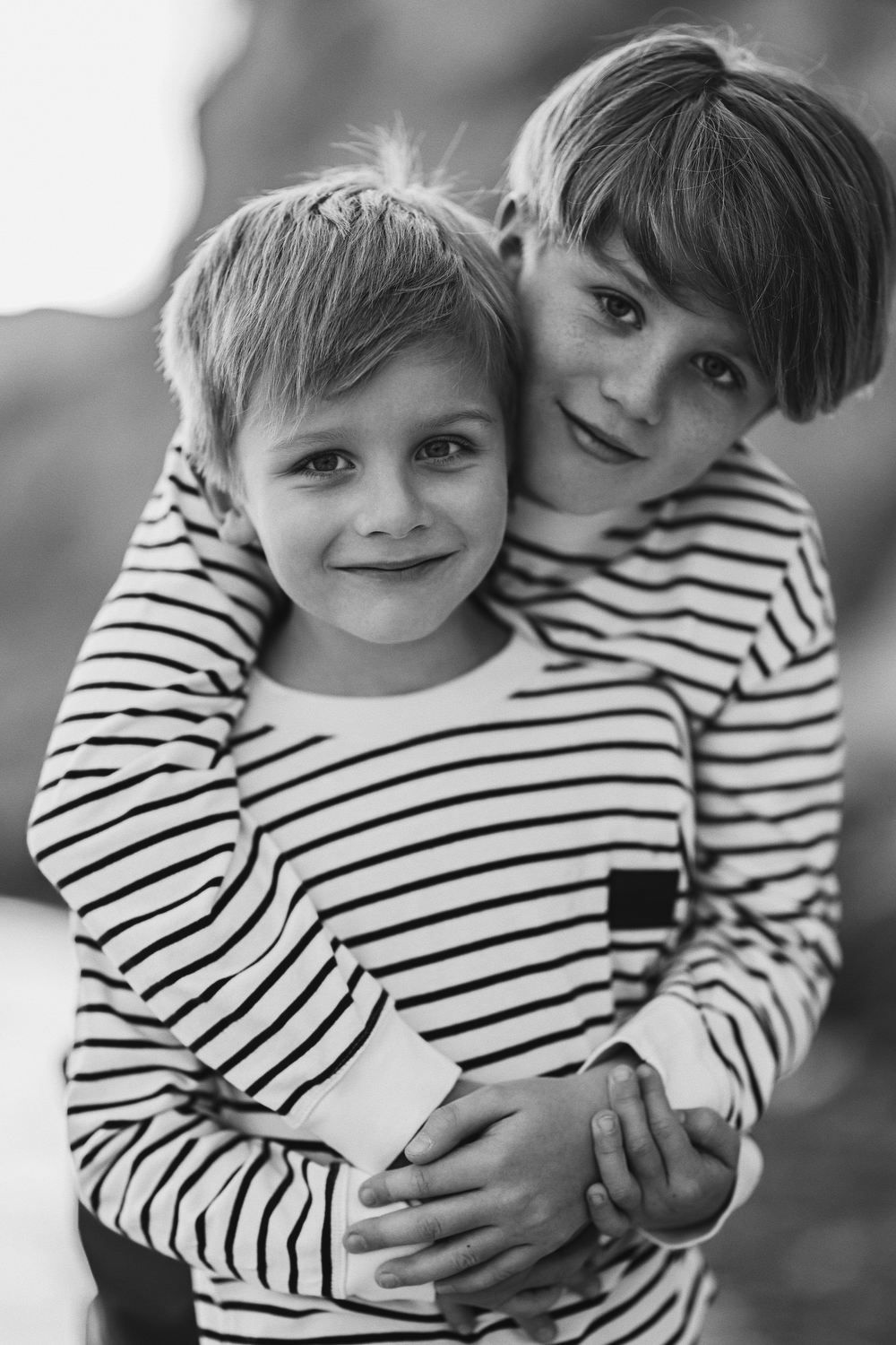 A heartwarming black and white portrait of two brothers hugging and smiling at the camera during their family holiday in Spain