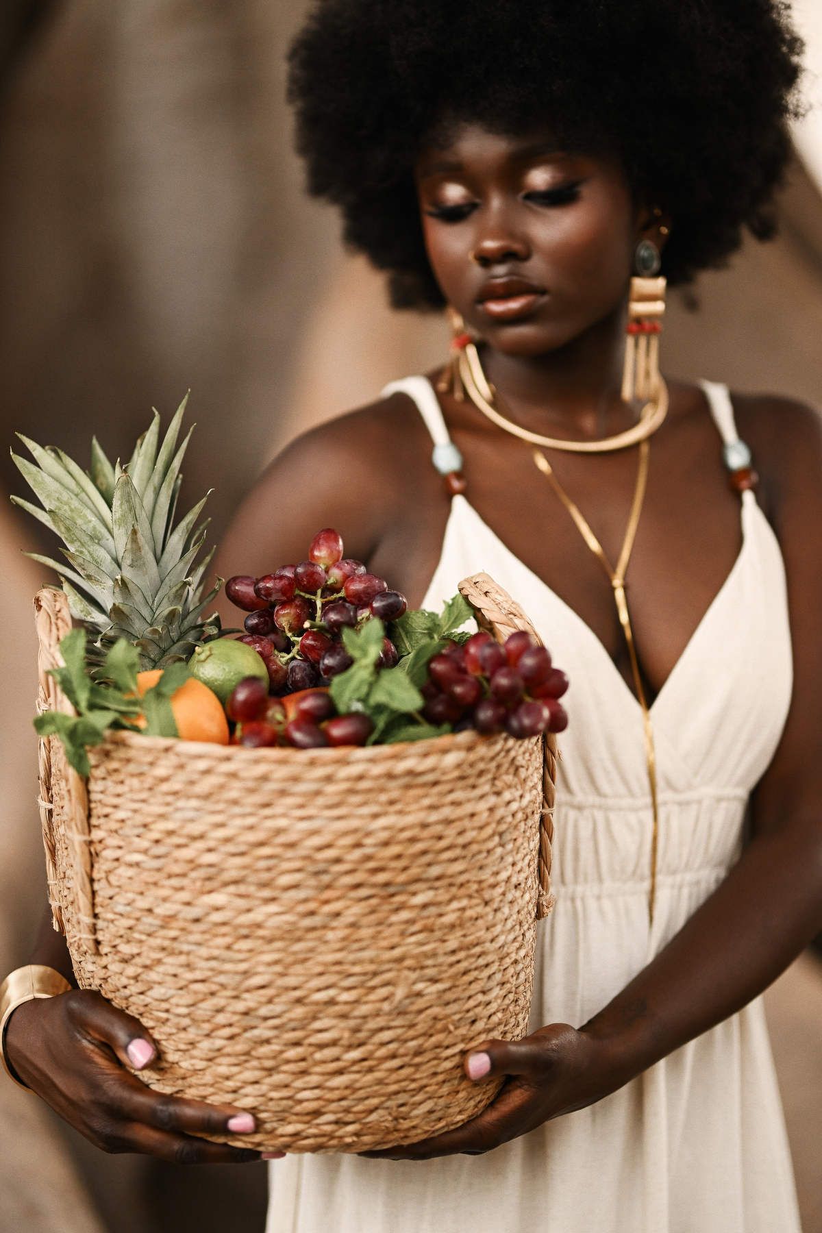 Close-up shot focusing on an intricate fruit basket and gold statement jewelry during a conceptual portrait session in Valencia.