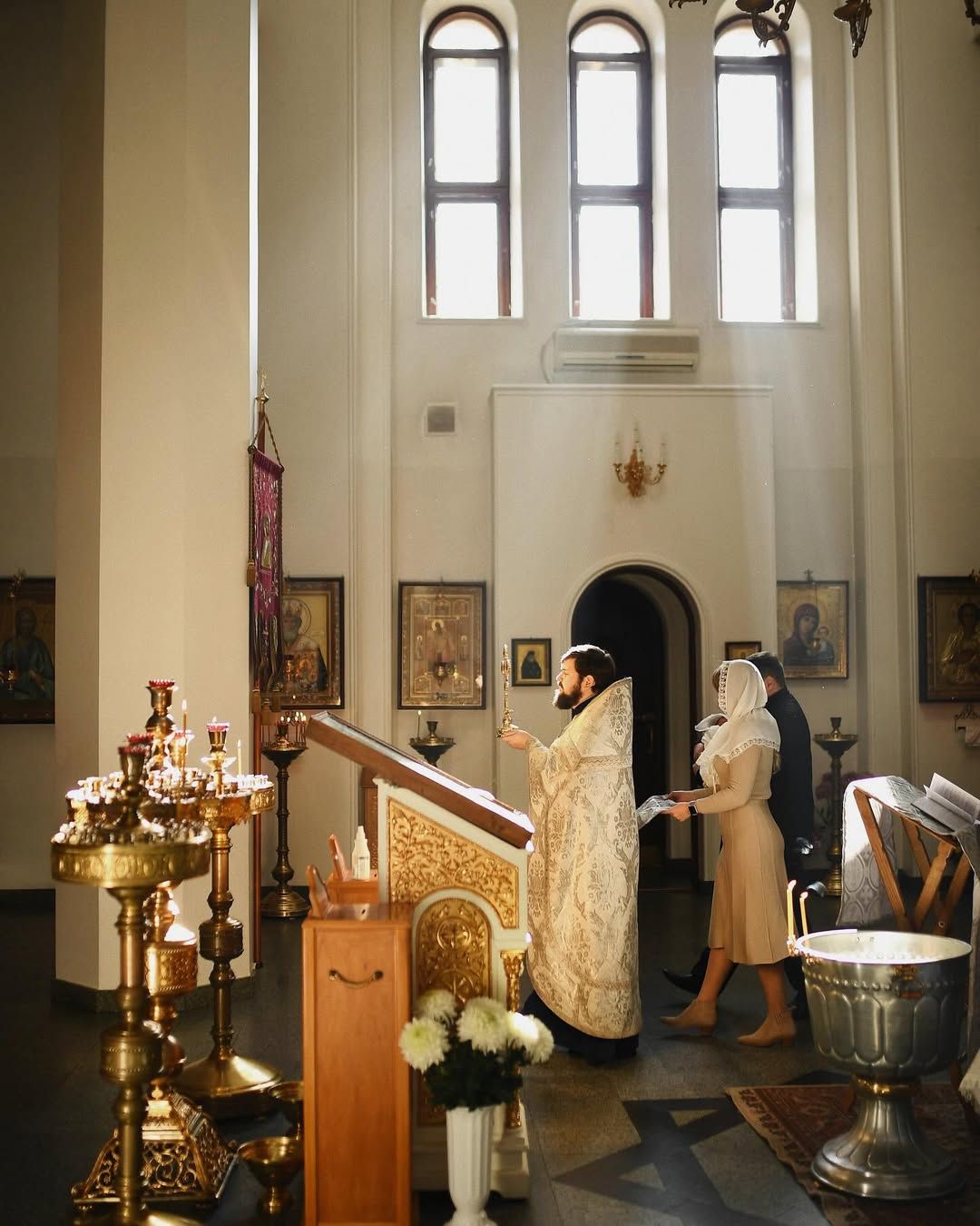 Priest leading the godparents and baby through a traditional baptism ceremony inside a beautiful church in Valencia