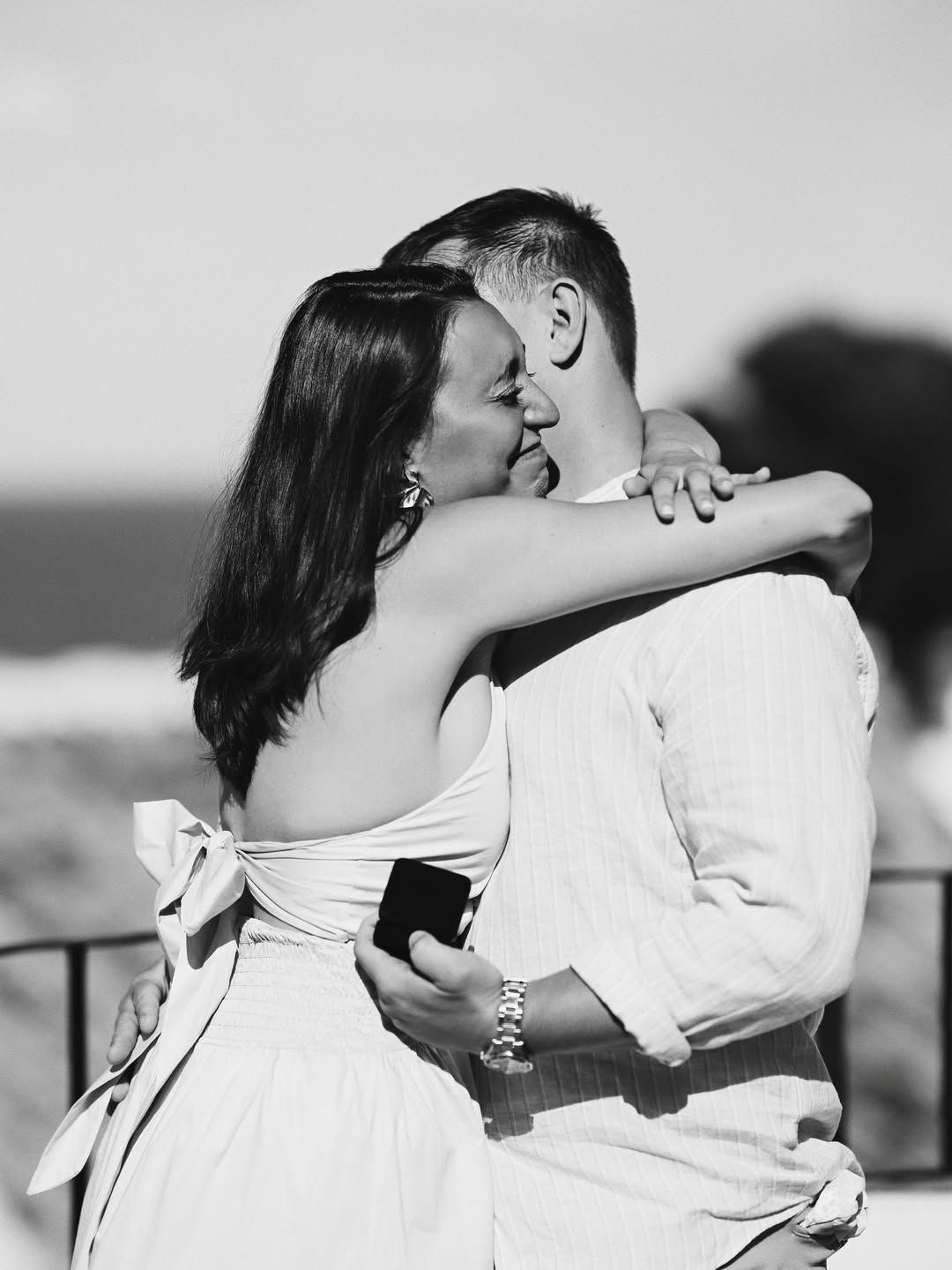 An emotional black and white shot of a couple embracing immediately after a surprise marriage proposal at a scenic location in Valencia.