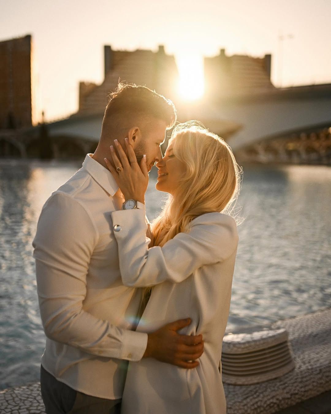 A couple about to kiss against a stunning golden hour sun flare by the water at the City of Arts and Sciences