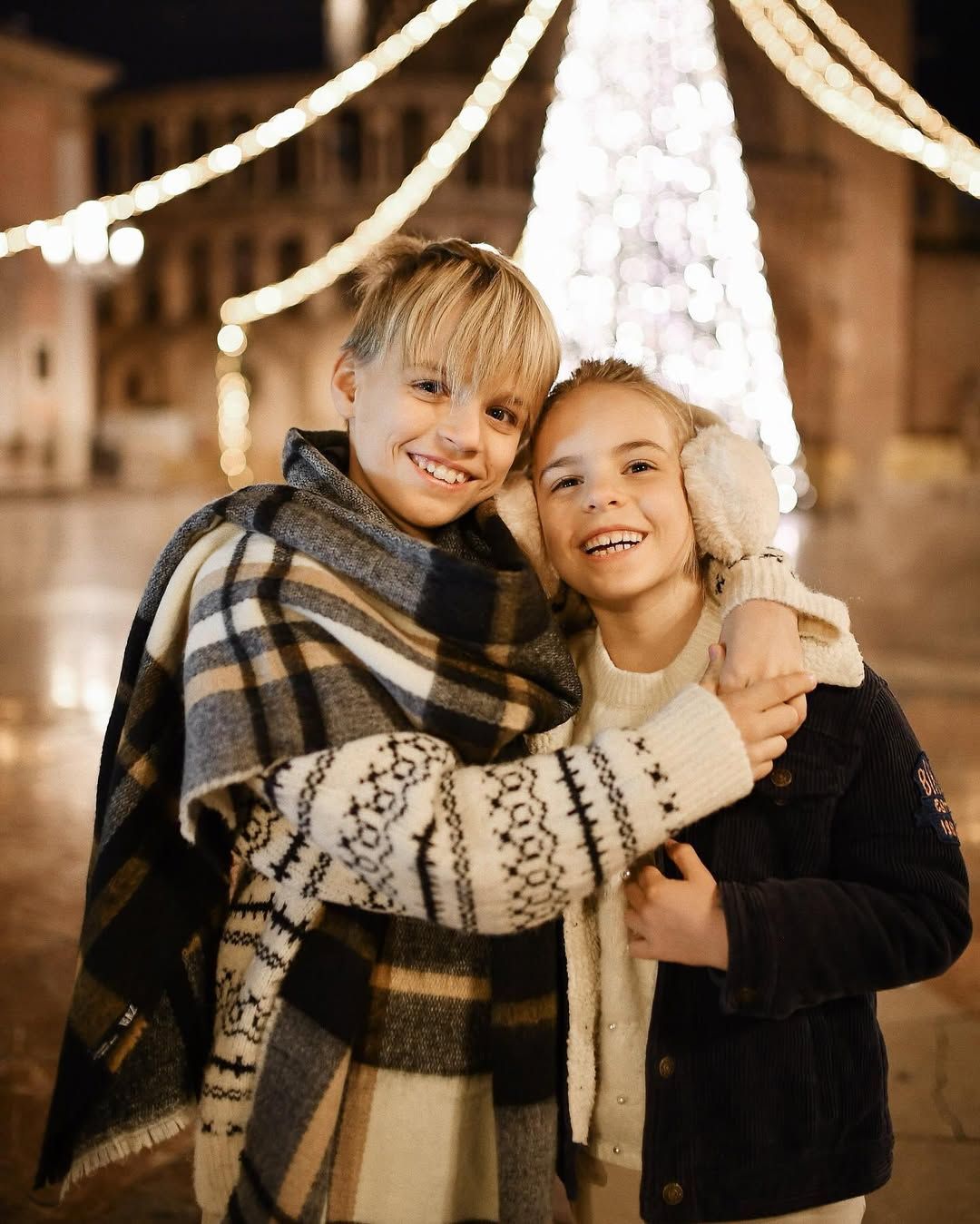 Brother and sister warmly hugging and smiling at the camera during an outdoor New Year and Christmas family photoshoot in Valencia