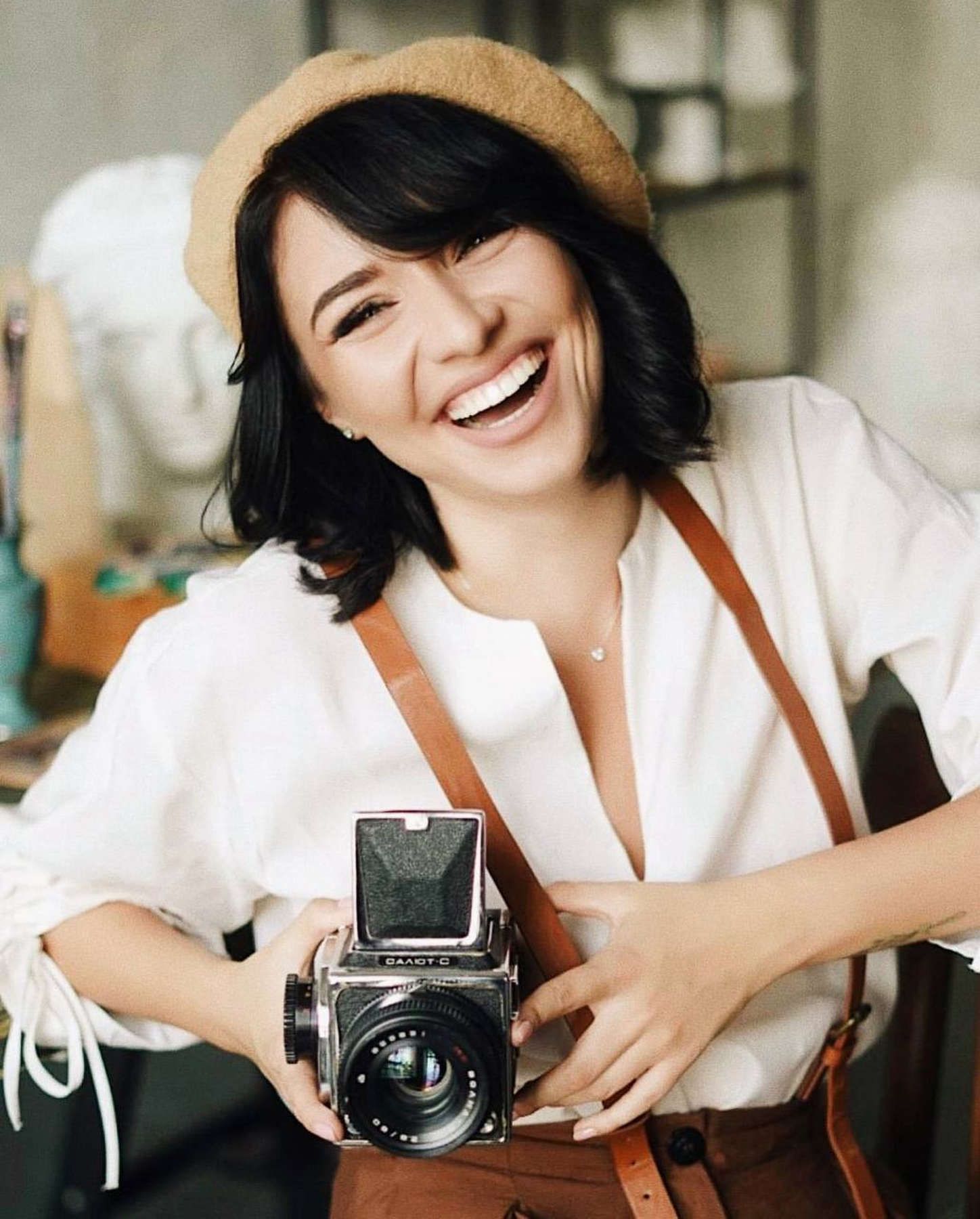 Smiling photographer Darina Derzkaya holding a vintage medium format film camera during a creative lifestyle portrait session.