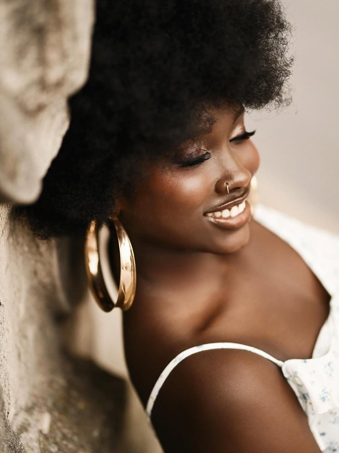 Close-up side profile of a smiling woman with an afro and large gold hoop earrings during a portrait session in Alicante.