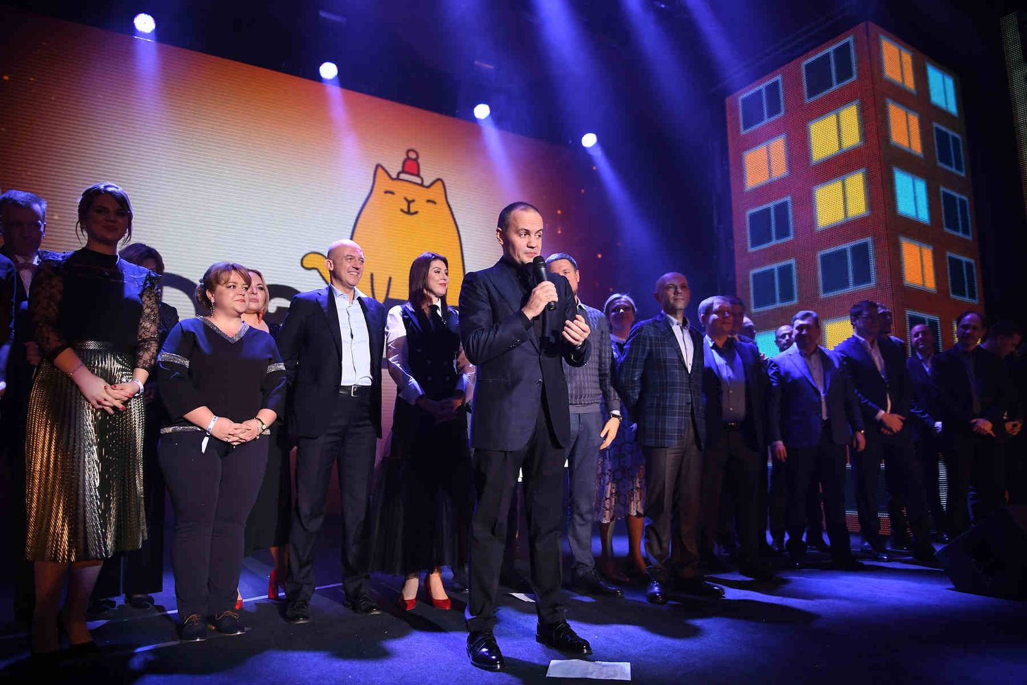Professional keynote speaker with a microphone addressing the audience on stage during a large corporate gala in Valencia.