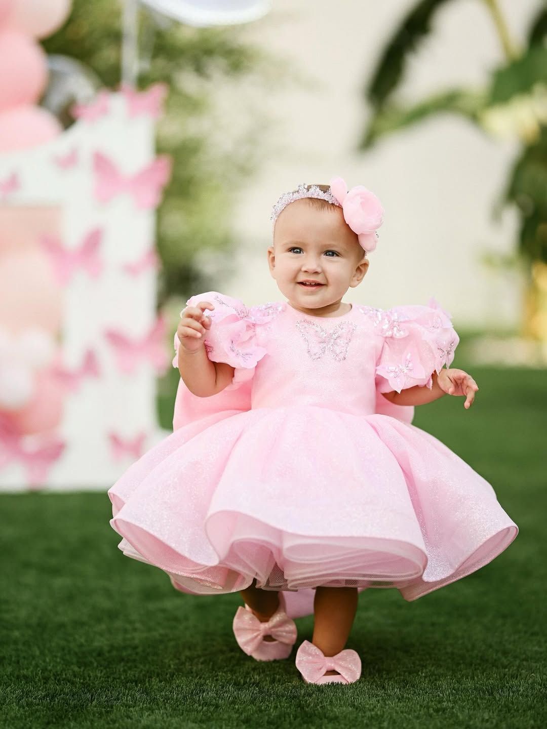 Joyful toddler girl running and smiling on the grass during an outdoor lifestyle children's photoshoot.