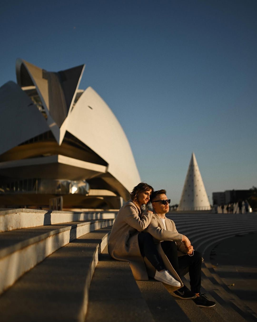Golden hour couple photoshoot at the City of Arts and Sciences in Valencia, featuring the pair sitting on concrete steps.