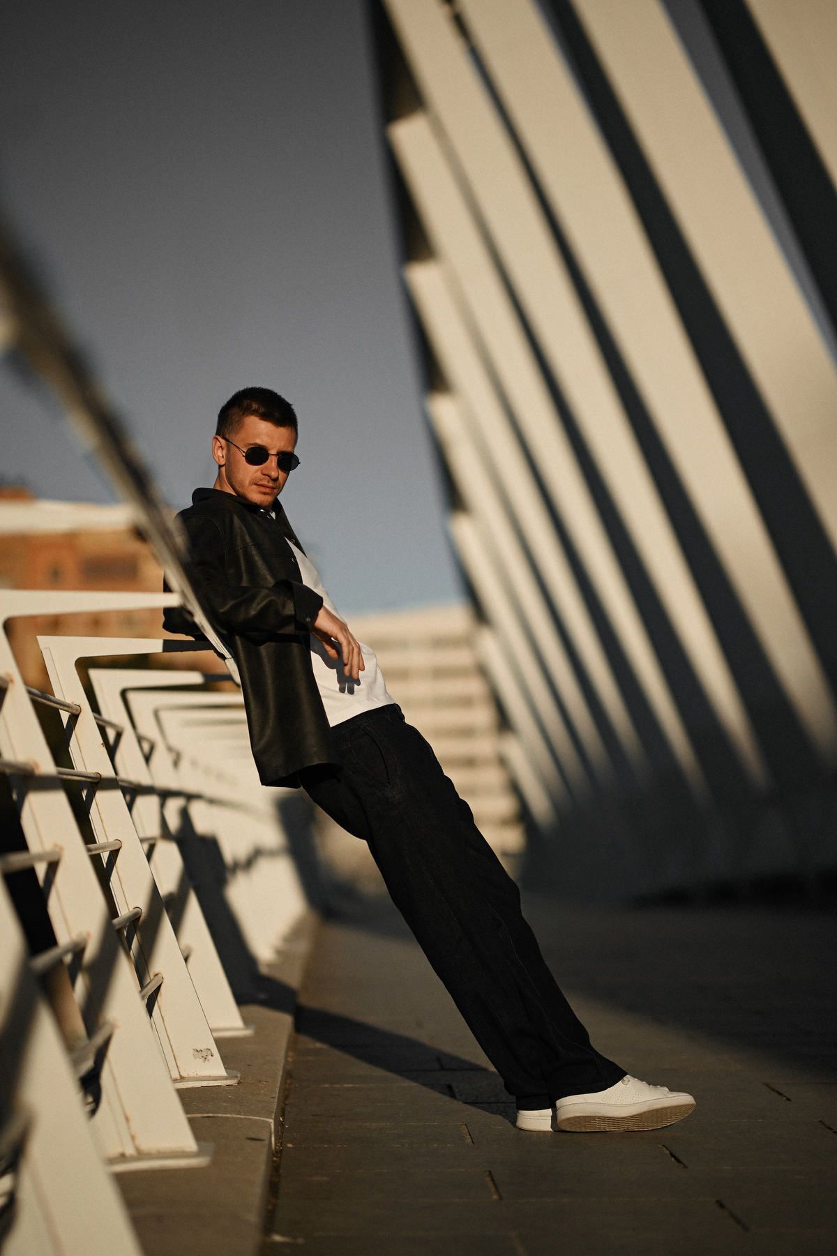 Male portrait on the futuristic bridge of the City of Arts and Sciences, capturing the rhythmic modern architecture of Valencia.