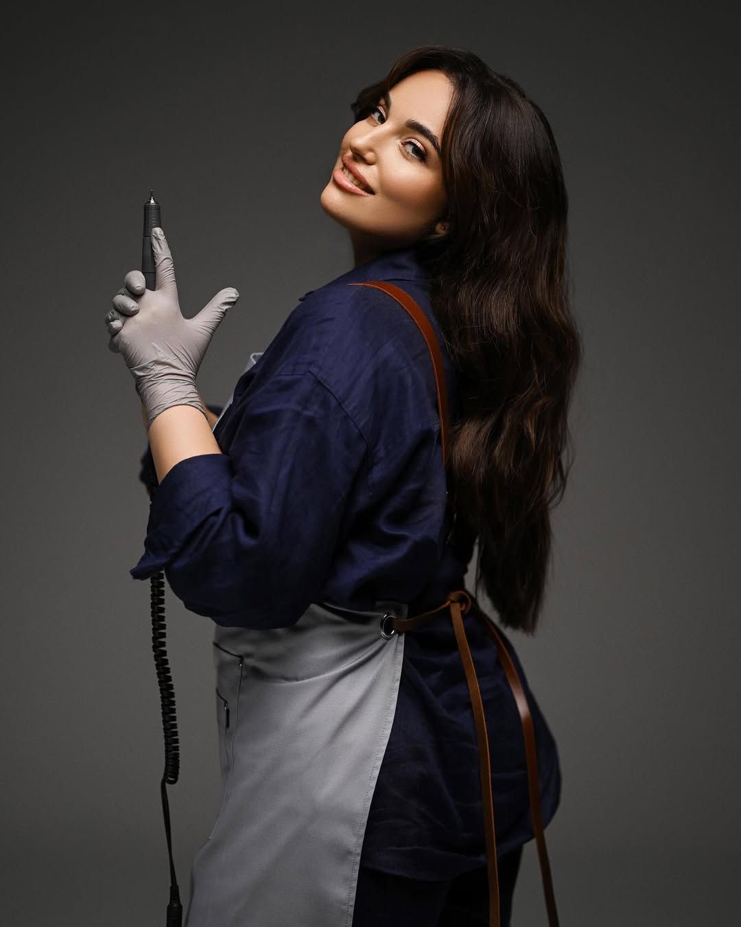 A nail technician holding a professional electric nail file, showcasing the dedicated process and tools of a creative maker.