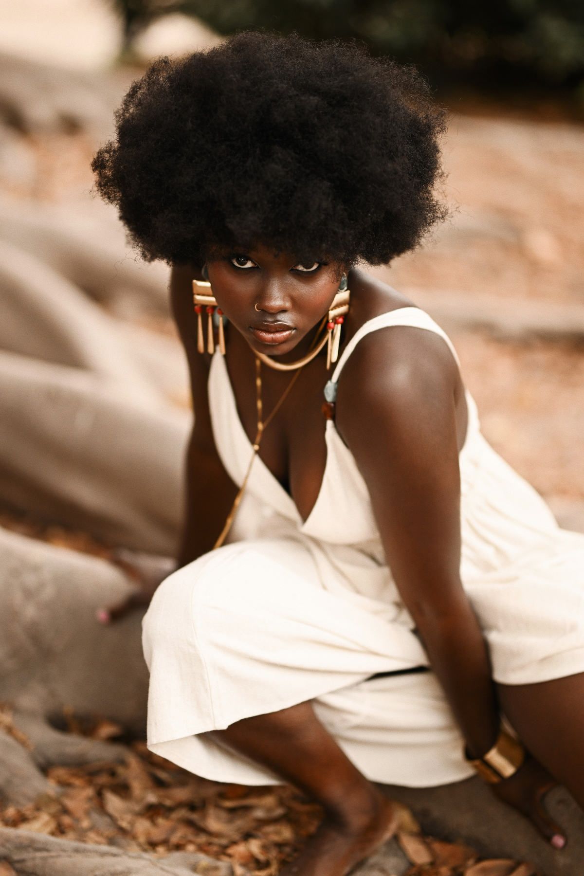 Intense close-up portrait of a crouching model with bold geometric earrings during a conceptual portrait session in Spain.