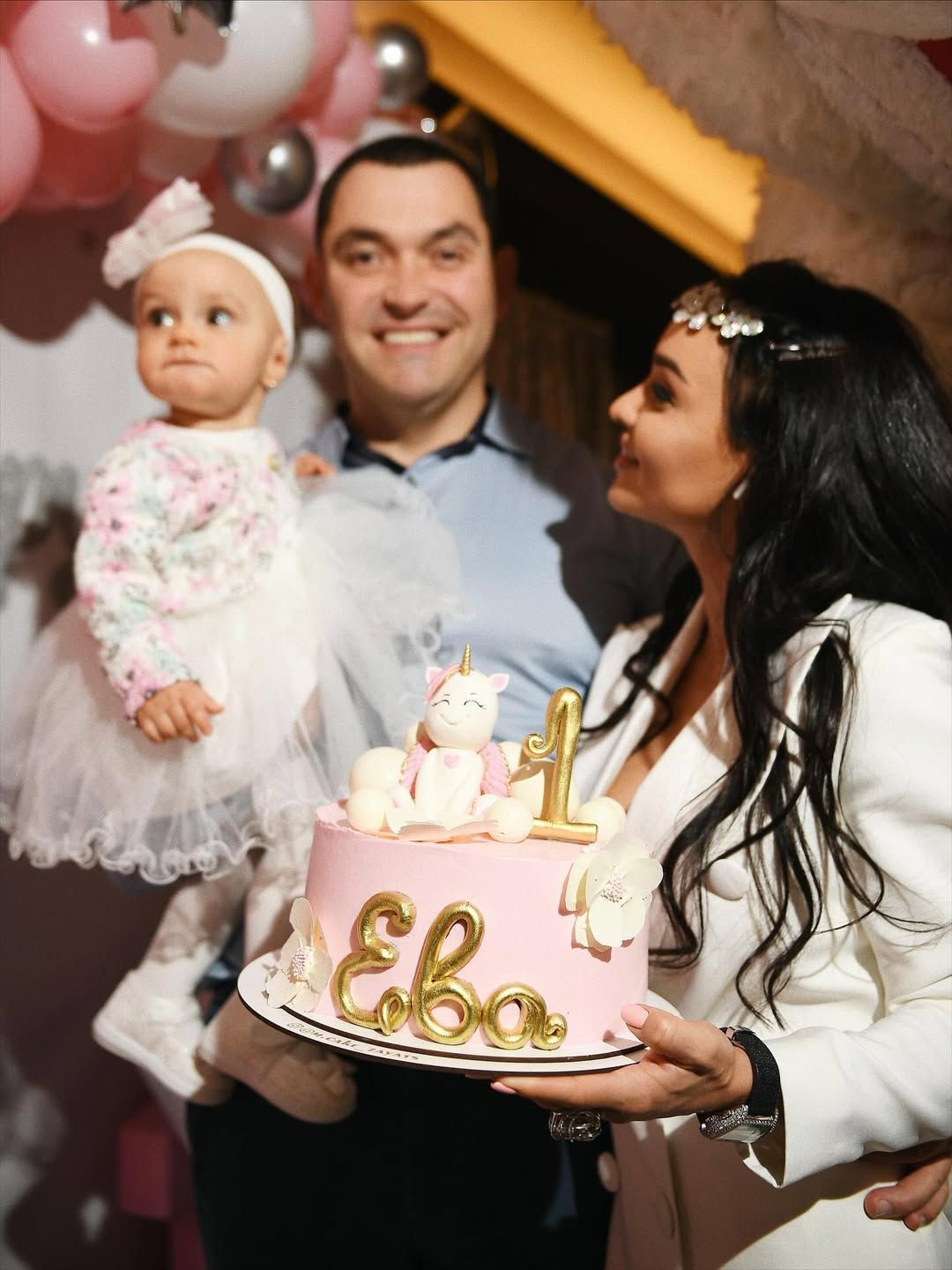 Happy family presenting a custom pink unicorn birthday cake at a premium children's event in Valencia.