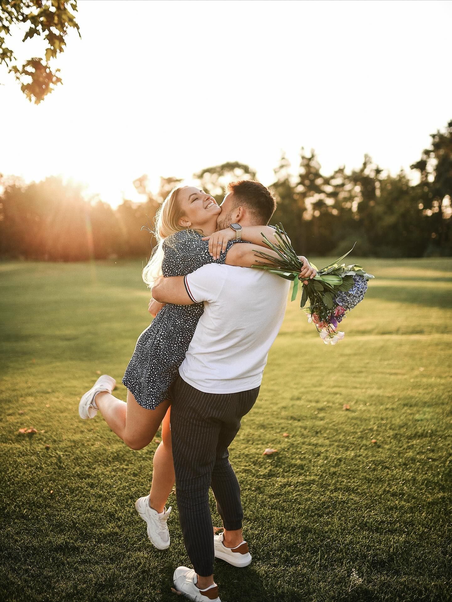 A romantic and emotional embrace between a newly engaged couple after a successful marriage proposal in a park in Valencia.