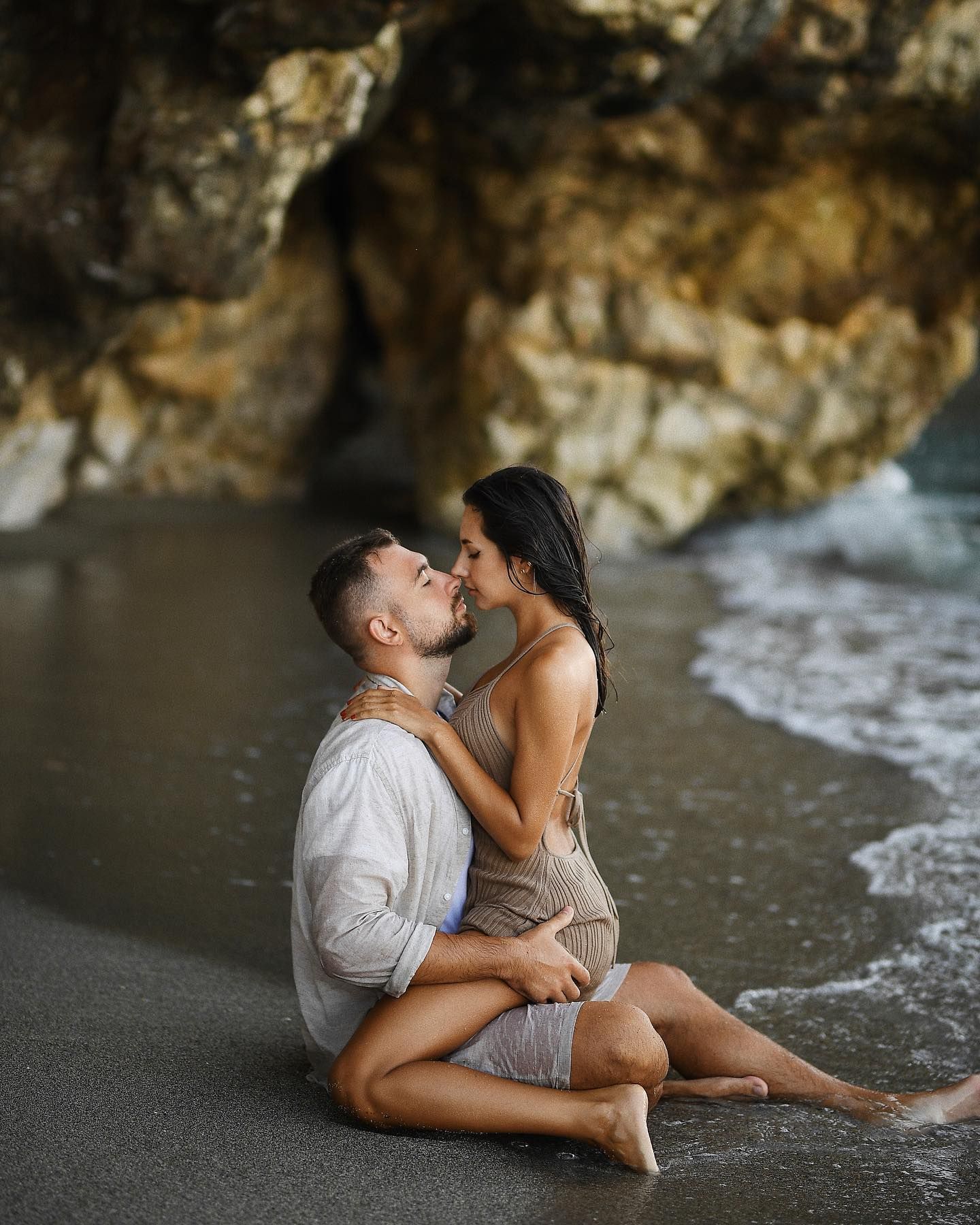 An intimate honeymoon photoshoot moment showing a loving couple sitting together in the shallow waters of the Valencia coastline.