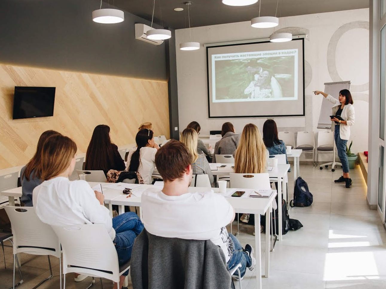Photography mentorship business class featuring a speaker presenting educational slides on a projector to a seated audience.