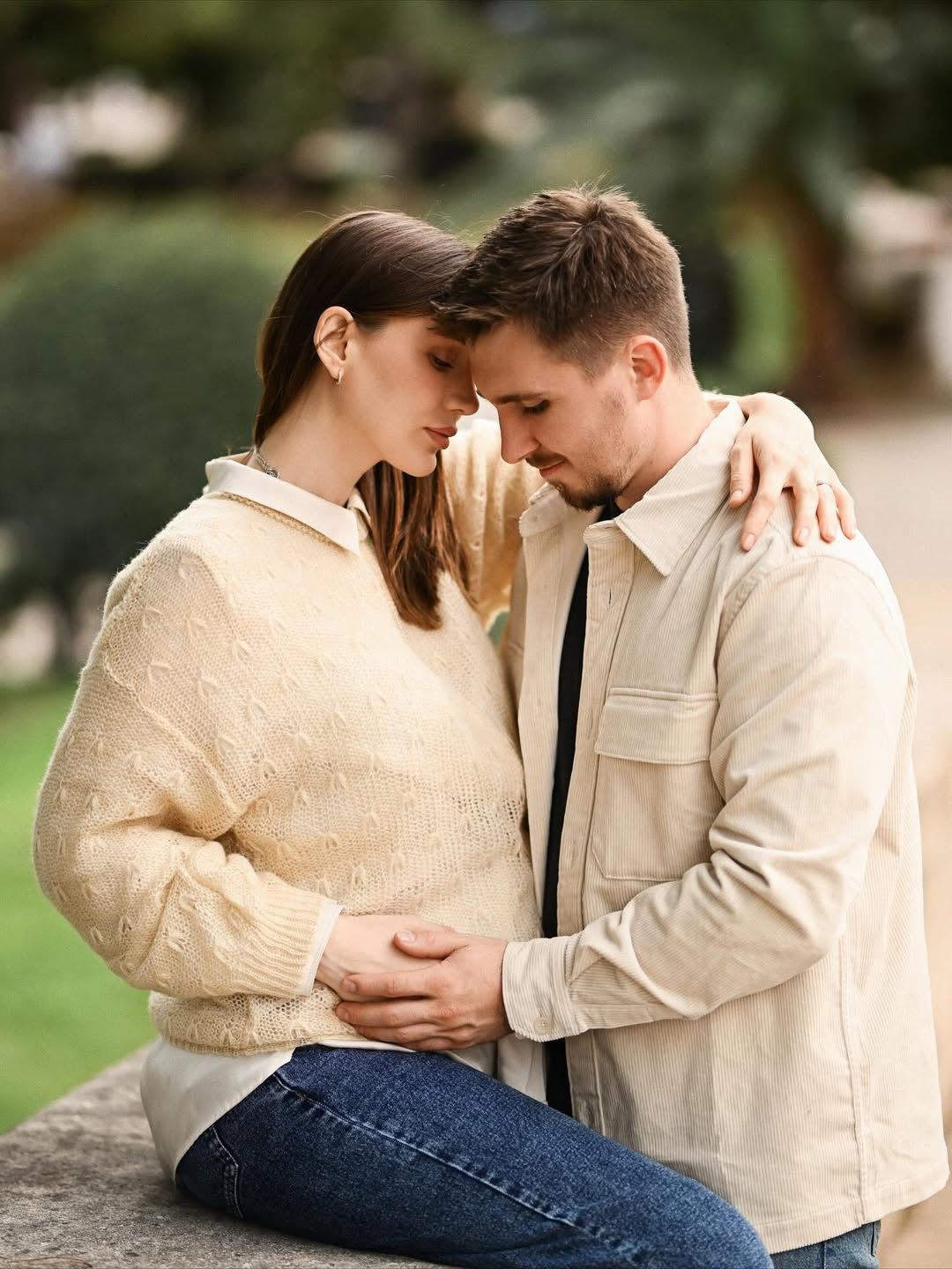 Intimate maternity portrait in Turia Park, Valencia with the expecting couple holding the baby bump in soft filtered evening light.