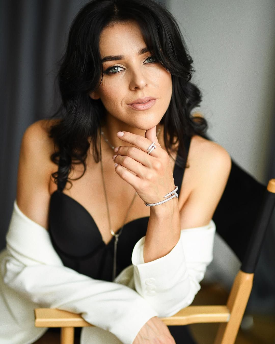 Luxury boudoir photoshoot in Valencia. A woman with elegant jewelry and an off-shoulder blazer poses for a fine art portrait.