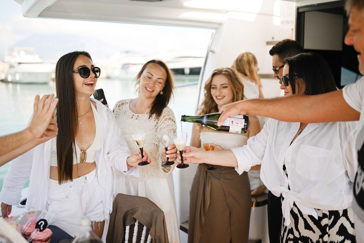 Friends pouring champagne and celebrating a baby shower and gender reveal party on a private yacht in Valencia, Spain.