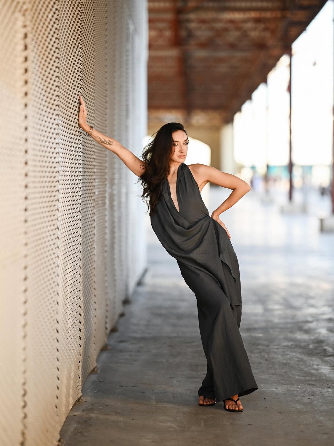 Editorial fashion portrait of a woman leaning against the modern textured walls of Veles e Vents