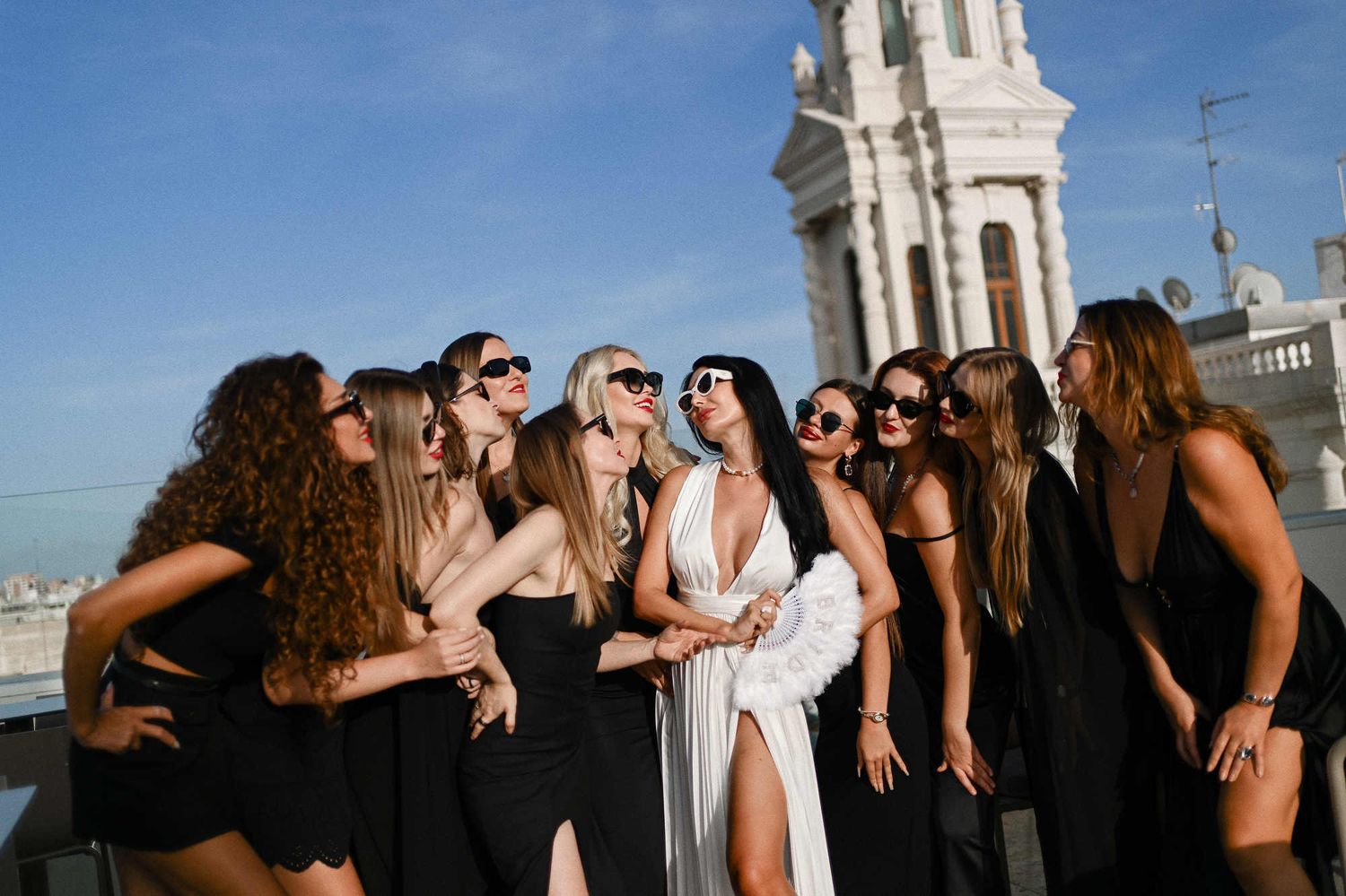 Fun bachelorette session on a Valencia rooftop, showing bridesmaids in sunglasses hugging the bride with city views.
