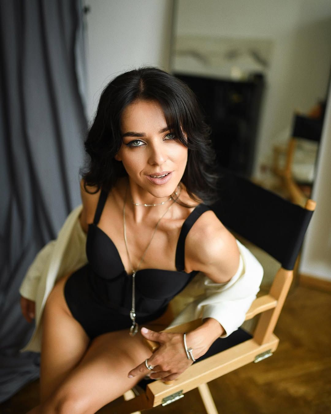 Fine art boudoir portrait in Valencia. A woman in a black bodysuit and white blazer sits confidently in a private photography studio.