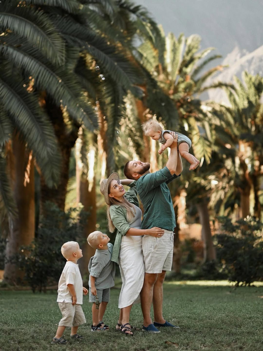 A father tossing his baby in the air while the mother and two boys watch in Turia Park, Valencia.