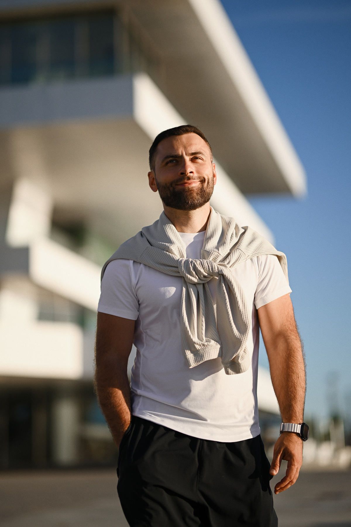 Relaxed portrait of a man at Valencia port during golden hour sunset light, wearing a casual t-shirt and athletic pants.
