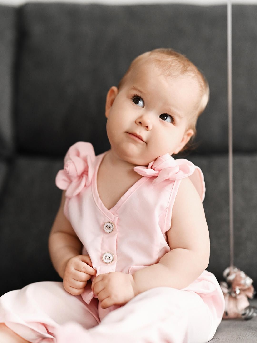 Elegant close-up portrait of a baby girl in a pink dress looking up during her home birthday party.