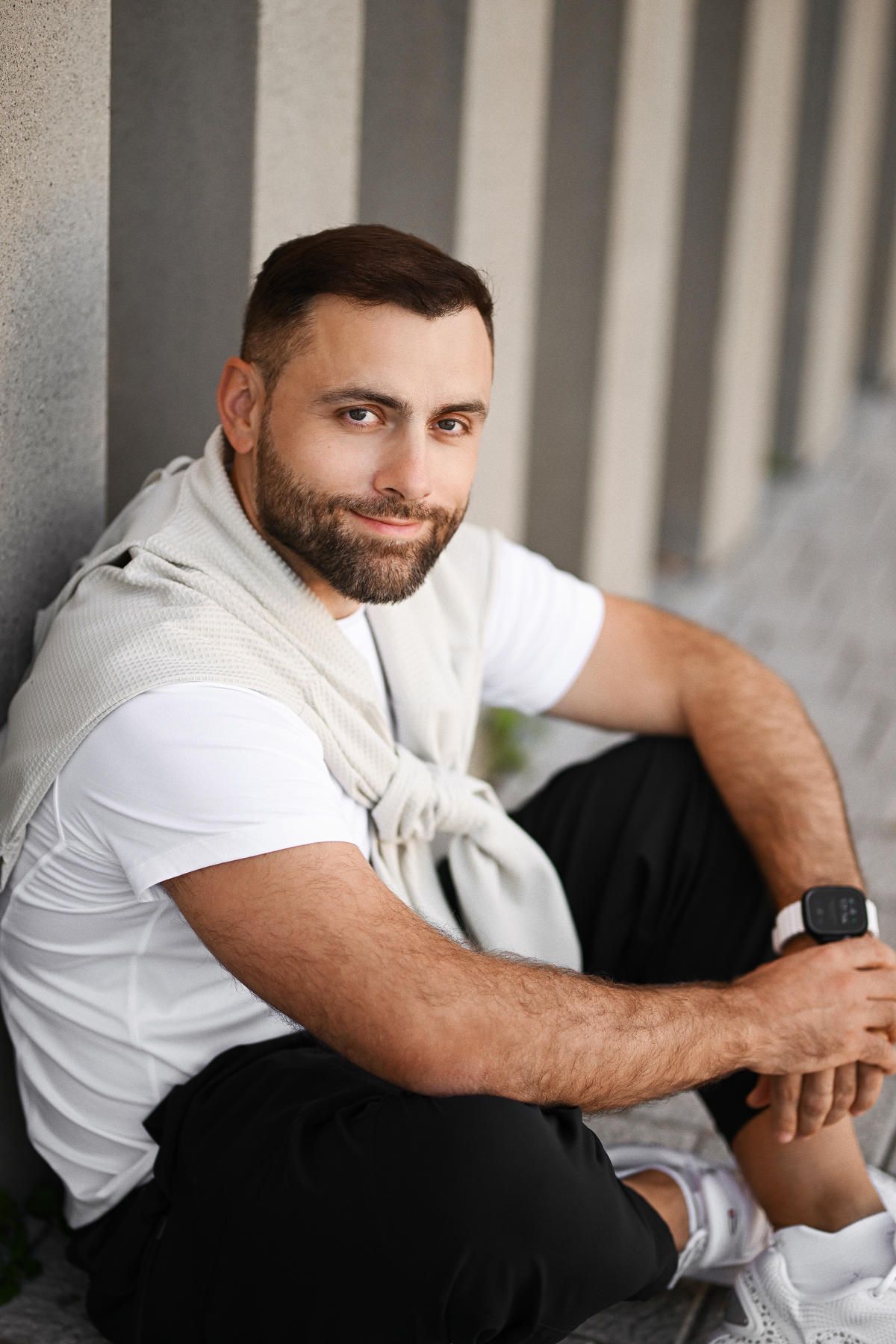 Urban portrait of a man posing against modern concrete architecture and minimalist city center buildings in Valencia.