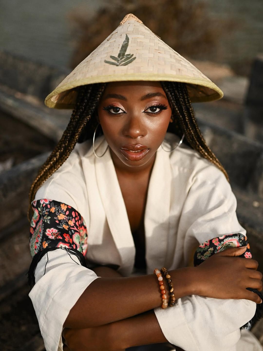 High-fashion portrait of a Black woman with braided hair and professional makeup sitting in a wooden boat in Albufera, Valencia