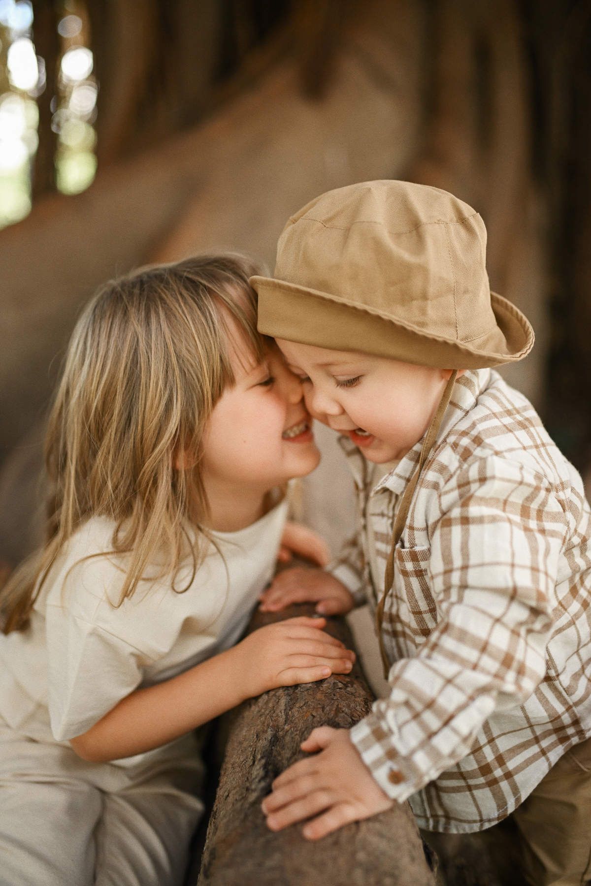 A sweet moment between siblings as a little girl and her toddler brother touch noses next to a tree in Viveros Park.