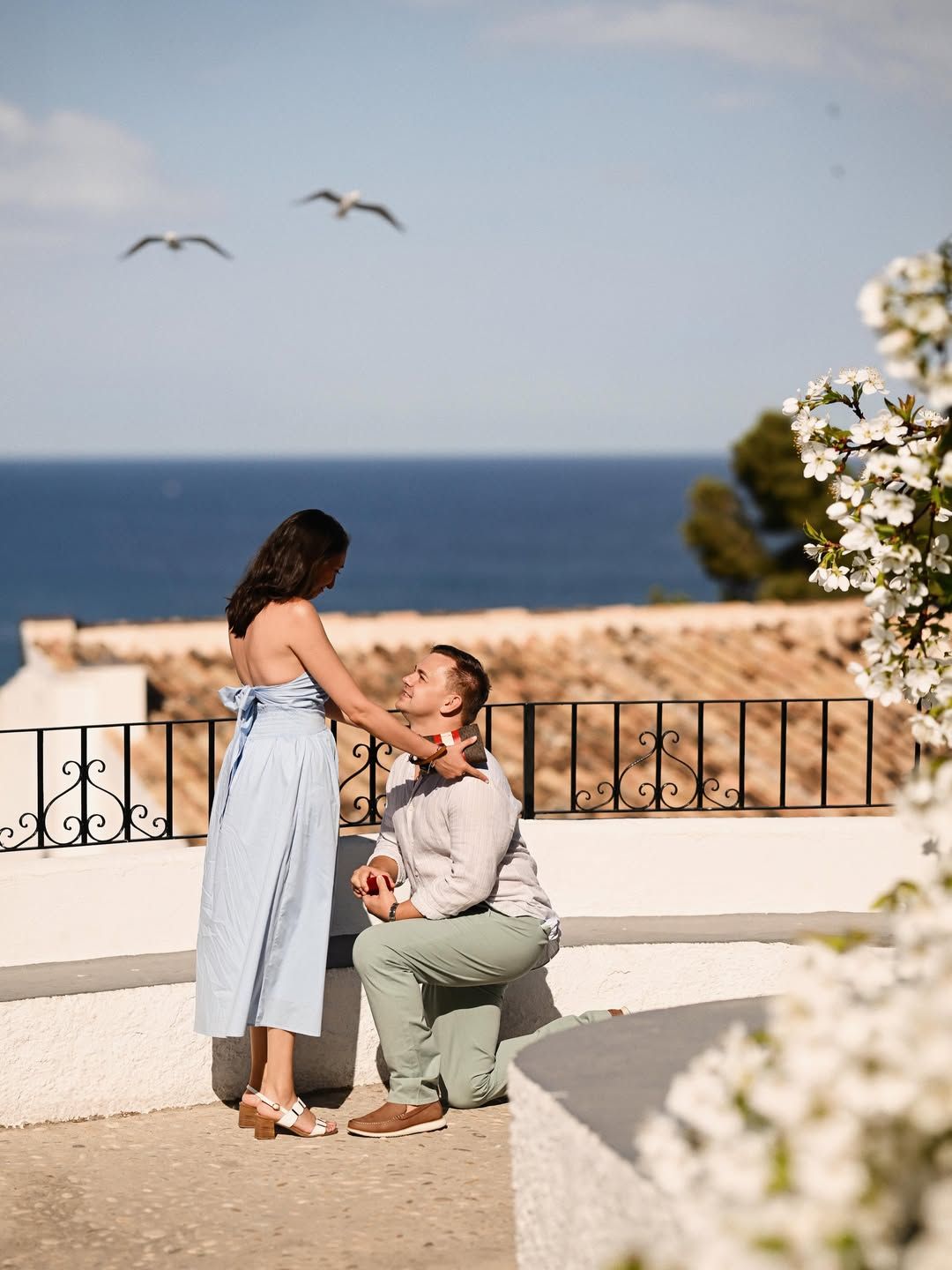 A man kneeling to propose to his partner on a scenic terrace overlooking the Mediterranean sea during a professional proposal in Valencia.