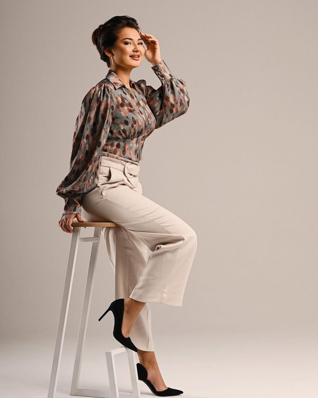 A versatile business portrait of a woman sitting on a stool, perfect for high-level corporate and social media engagement.