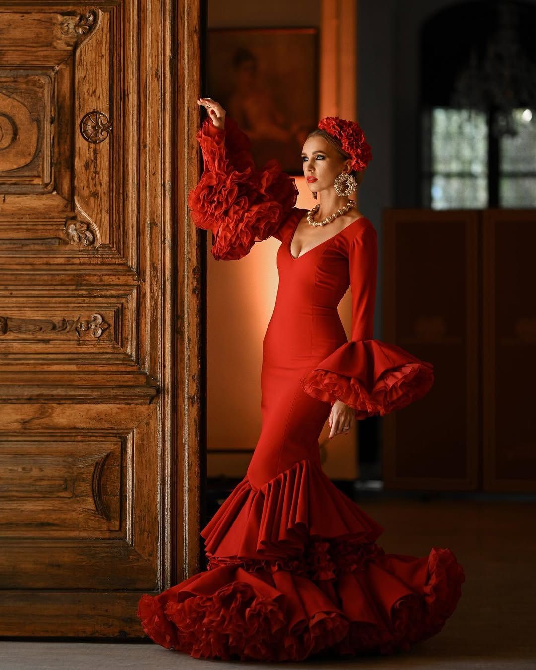 A stunning contrast of a red dress against the rich texture of a massive antique wooden door at Villa Montemolar