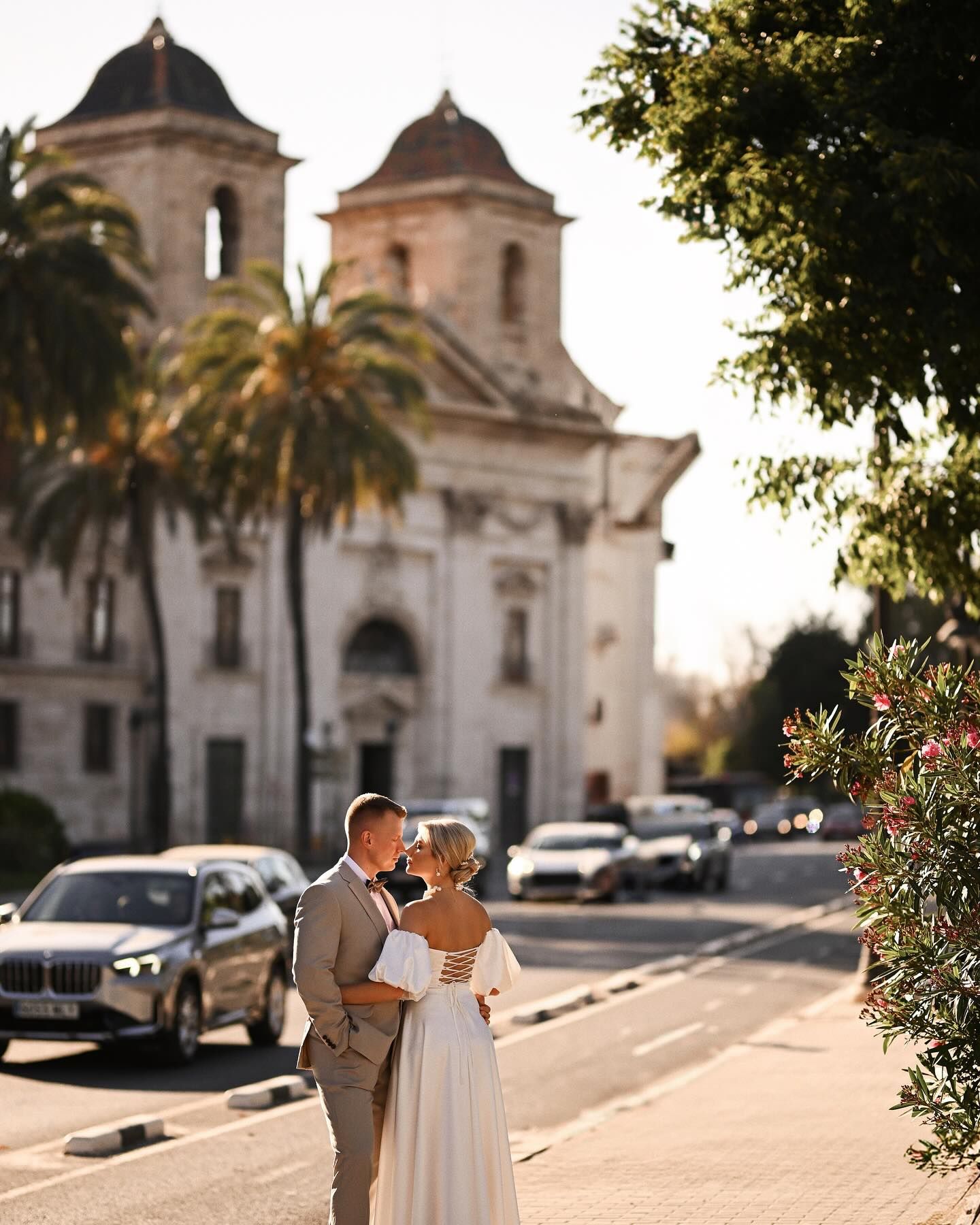 A newlywed couple stands together in a sunlit historic square in Valencia, capturing the relaxed pace of an authentic city elopement.