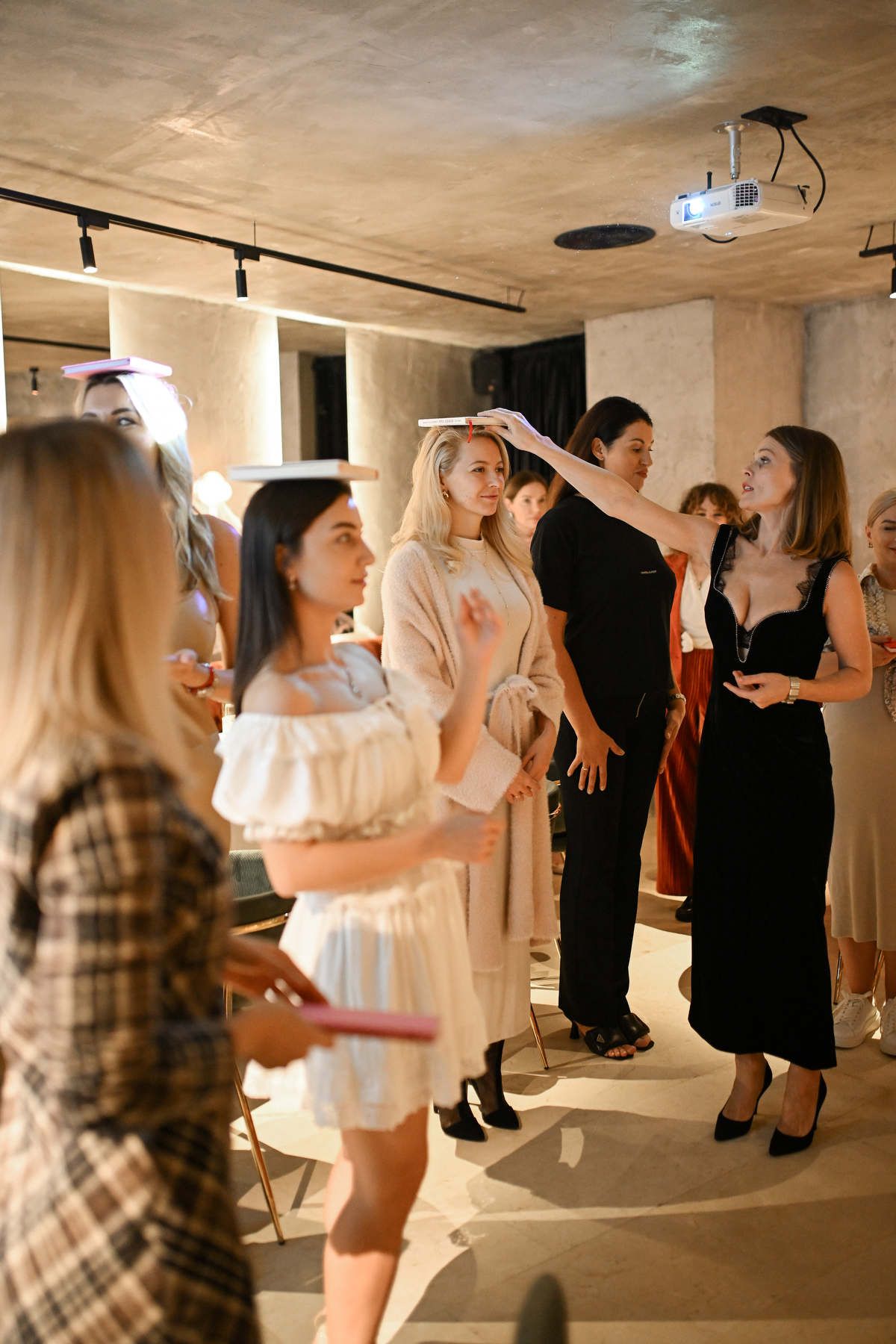 Female participants balancing books on their heads during an interactive game at a corporate team-building event.