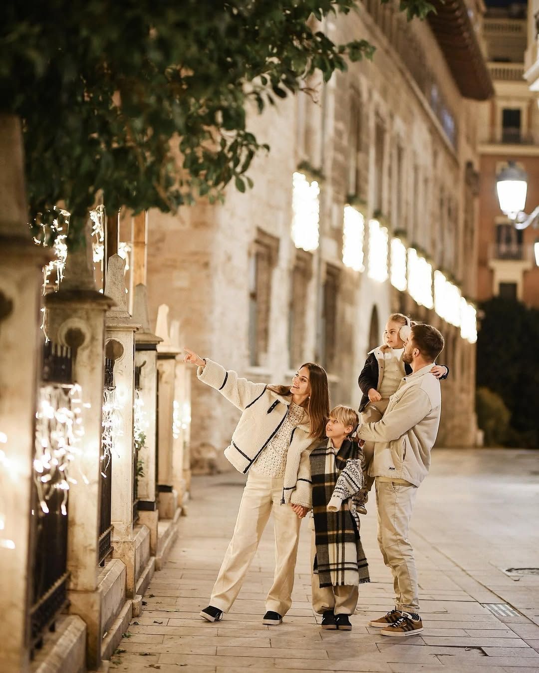Happy family walking down a beautifully illuminated historic street during a twilight Christmas portrait session in Valencia