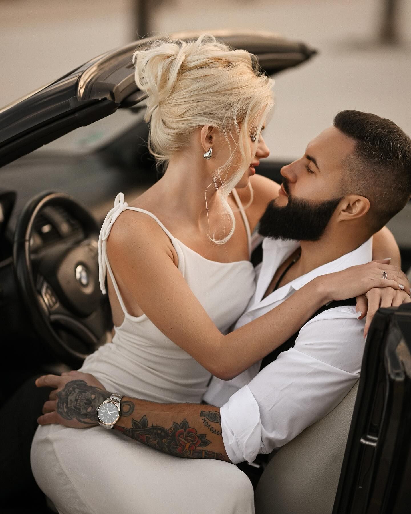 A romantic couple sitting together and embracing inside a black luxury convertible car during an editorial elopement in Valencia.