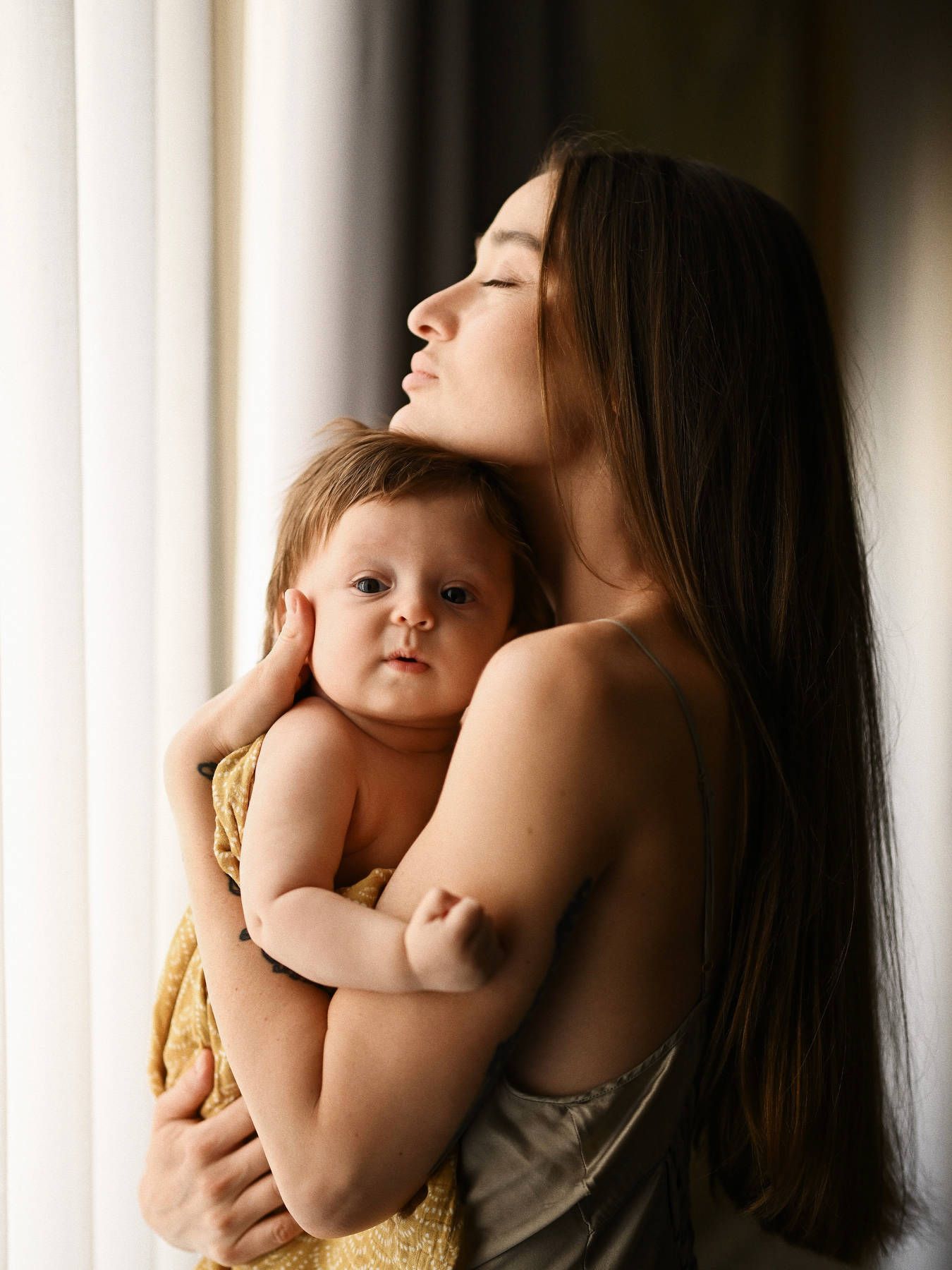 A tender portrait of a mother gently cradling and hugging her baby, showcasing an intimate and loving connection.