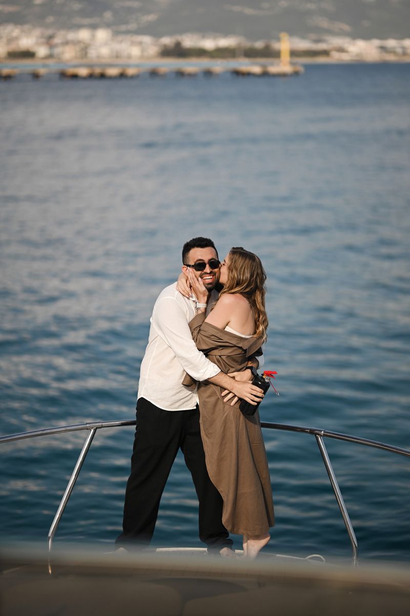 Woman kissing her partner after a blue smoke gender reveal on a yacht in Valencia, capturing the genuine emotional reaction.